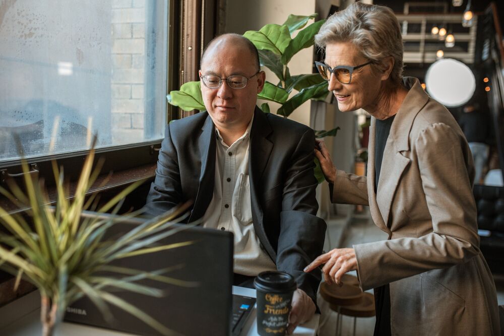 Two colleagues reviewing retirement plans together at a laptop